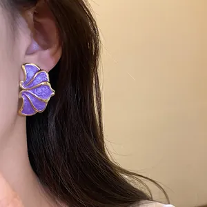 Detailed macro view of vintage purple enamel flower stud earrings with silver needles