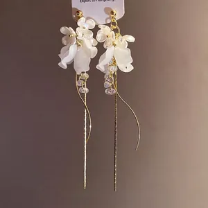 Elegante weiße Blumenohrringe mit langen goldenen Quastenketten für stilvolle Damen