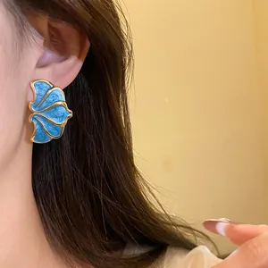 Detailed macro view of vintage blue enamel flower stud earrings with golden metallic trim