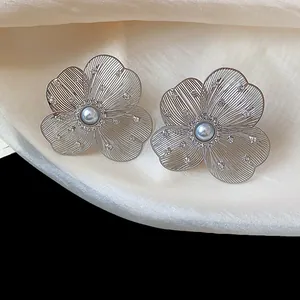 Detailed macro view of silver hollow flower stud earrings with pearl and rhinestones