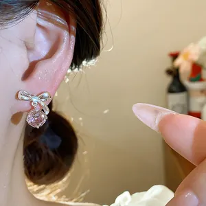 Vista dettagliata di eleganti orecchini a lobo a fiocco in argento con zircone rosa.