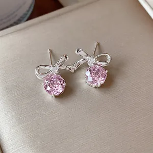 Dettaglio di orecchini a lobo con fiocco d'argento e fiori di zircone rosa brillanti.