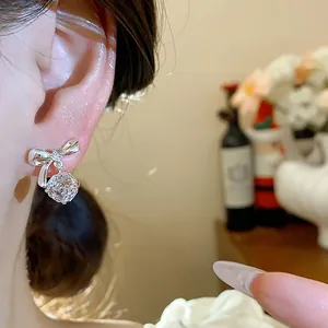 Primo piano di eleganti orecchini a fiocco d'argento con goccia di zircone