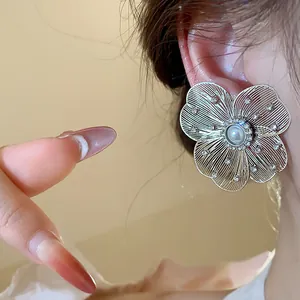 Macro detail view of an elegant hollow silver flower earring with central pearl and rhinestones