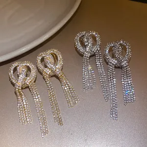 Close-up of luxurious full rhinestone bow earrings with long sparkling tassels hanging down