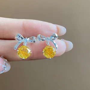 Dettaglio delle orecchini a fiocco in argento con pietre di zircone giallo rotonde
