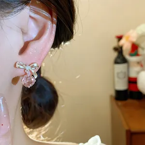 Primo piano di orecchini a fiocco in argento con fiore di zircone rosa indossati all'orecchio