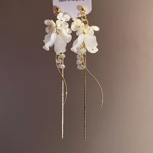 Nahaufnahme von eleganten weißen Blüten-Quastenohrringen mit goldenen langen Kettendetails