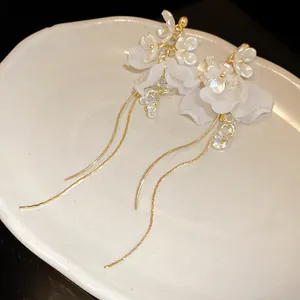 Detailansicht der französischen Retro-Ohrringe mit weißen Blumen und Goldquasten
