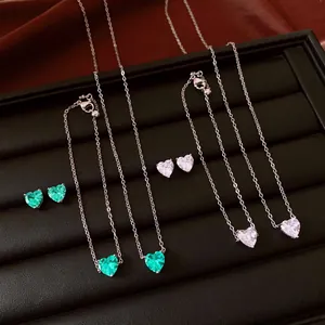 Détail d'un ensemble de bijoux en argent avec zircons en forme de cœur verts et clairs.