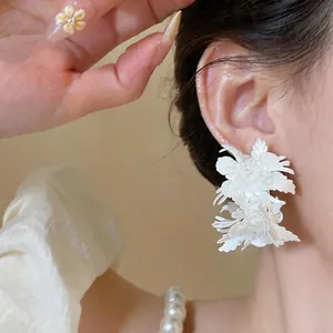 Close-up detail of vintage style white leather multi-layer flower stud earrings