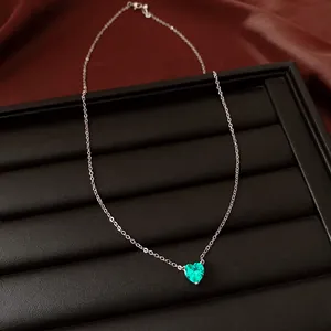 Gros plan d'un collier en argent avec pendentif zircon vert en forme de cœur.