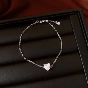 Détail macro d'un bracelet fin en argent avec un zircon en forme de cœur sur un présentoir.