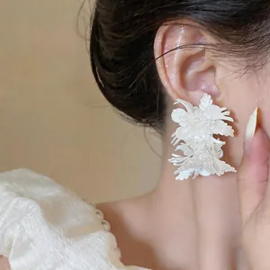 Detailed view of white leather floral stud earrings worn by model, vintage design