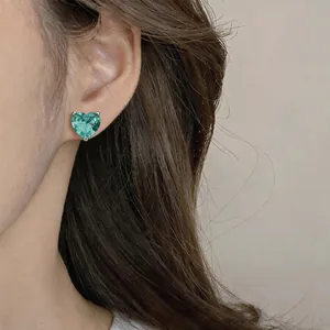 Détail macro d'élégantes boucles d'oreilles en zircon bleu en forme de cœur sur l'oreille.