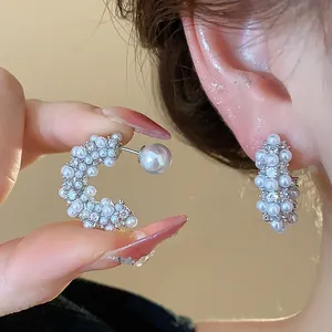 Macro view showing the intricate pearl and crystal detailing on C-shaped stud earrings