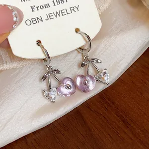 Close-up of sweet heart-shaped cherry earrings with sparkling crystals and pink resin.