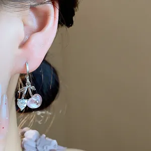 Close-up of sweet pink resin and crystal heart cherry drop earrings on model's ear