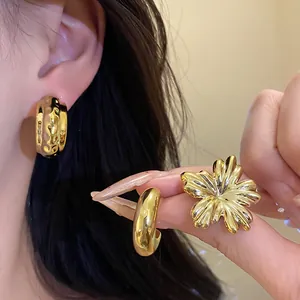 Elegant vintage gold flower and hammered hoop earring set displayed on model ear and hand