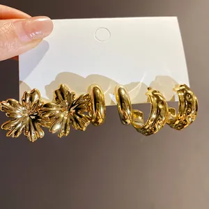 Close-up of vintage golden earring set featuring flower and textured hoop designs.