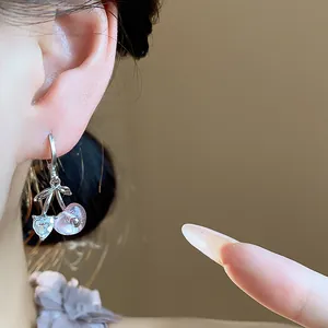 Close-up detail of a silver cherry earring with pink resin and heart crystal