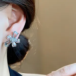Close-up detail of delicate silver needle flower earring with drop-shaped zircons