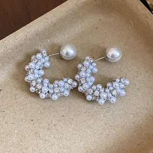 Elegant close-up view of French-style C-shaped stud earrings with pearls and crystals