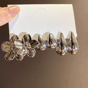 Close-up of three pairs of silver-tone earrings with flower and waterdrop shapes on card