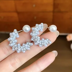 Close-up detail of French style C-shaped stud earrings with clustered pearls and crystal accents.