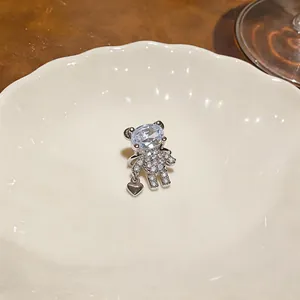 Dettaglio di un ear cuff a forma di orsetto con zirconi scintillanti e ciondolo a cuore