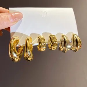 Close-up detail of three pairs of chunky gold-toned hoop earrings on a white card