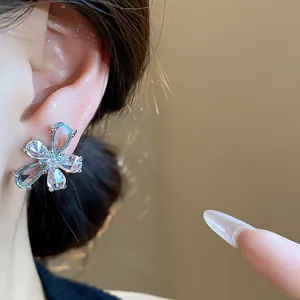Close-up detail of silver-toned flower stud earrings with sparkling clear zircons