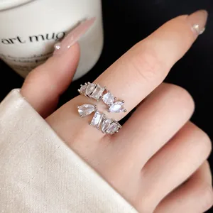 Close-up of a silver zircon open ring with various geometric stone cuts on a hand.
