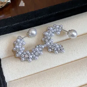 Detailed view of silver-toned C-shaped earrings embellished with pearls and crystals