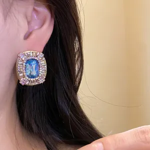 Orecchino a perno ovale vintage con pietra blu e cristalli indossato da modella