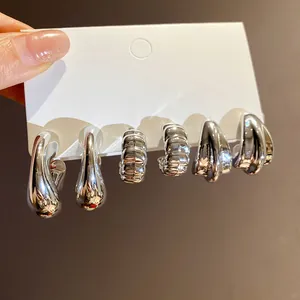 Detail showing a set of three pairs of silver-colored retro design earrings on a card
