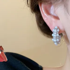 Detailed close-up of elegant C-shaped hoop earrings with white pearls and crystals