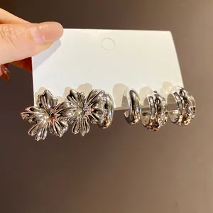 Close-up detail of vintage silver-tone flower and geometric hoop earring set for women