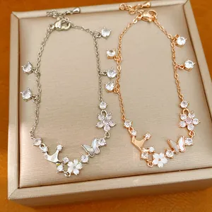 Detailed view of silver and rose gold bracelets featuring crown, butterfly, and flower charms