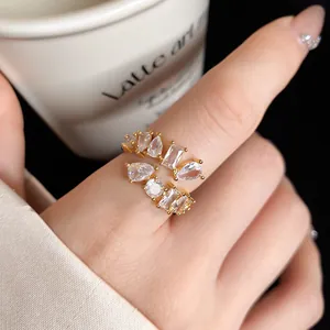 Macro detail of an elegant gold-plated open ring with multi-shape cubic zirconia.