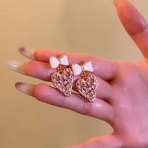 Vue rapprochée de boucles d'oreilles cœur scintillantes avec nœud blanc rose doré