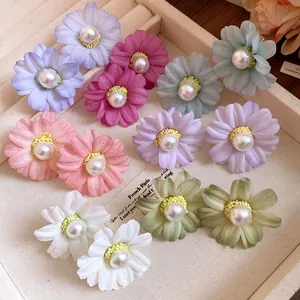 Close-up detail of multi-colored fabric flower stud earrings with elegant center pearls.