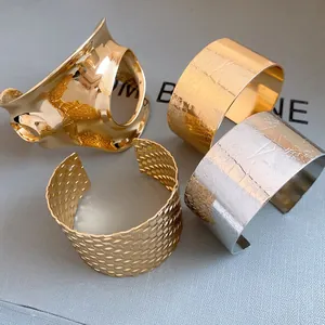Close-up of four assorted metallic open cuff bracelets in gold and silver finishes