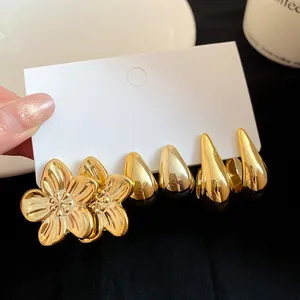Close-up of vintage gold flower and water-drop earring set on white display card