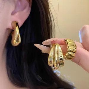 Close-up detail of vintage style gold teardrop earrings and a textured band ring set