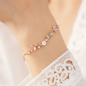 Close-up of elegant rose gold bracelet with zircon butterfly and flower charms on wrist