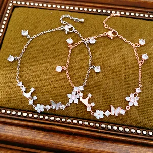 Detailed view of zircon-inlaid crown and butterfly charms on elegant bracelets
