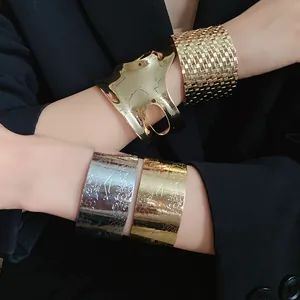Detail view of assorted gold and silver textured cuff bracelets on a model's arms.