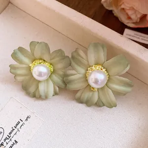 Macro view of vintage mint green fabric flower earrings featuring an elegant pearl center