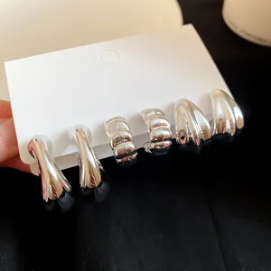 Macro shot of a three-pair silver earring set with textured and smooth finishes
